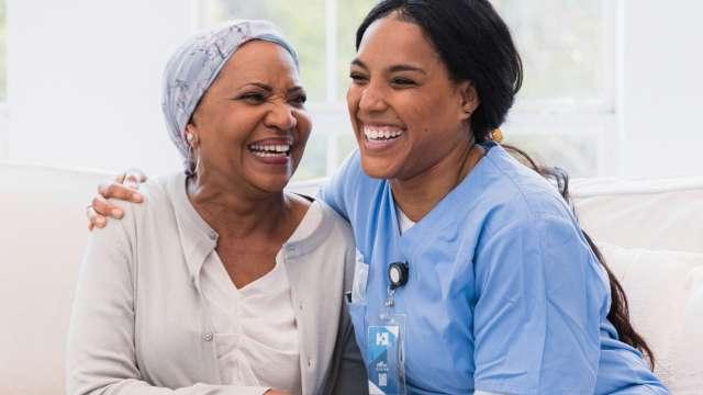 Female Cancer patient laughing with Nurse and holding hands