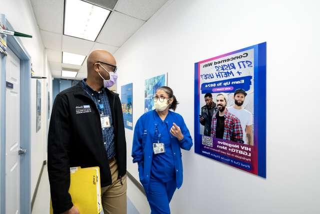 Clinical researcher Christopher Blades and laboratory coordinator Demetria Villanueva walk down a hallway of the Vine Street Clinic.