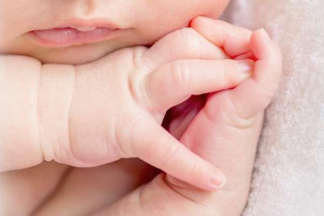 crossed fingers of a newborn baby asleep, closeup