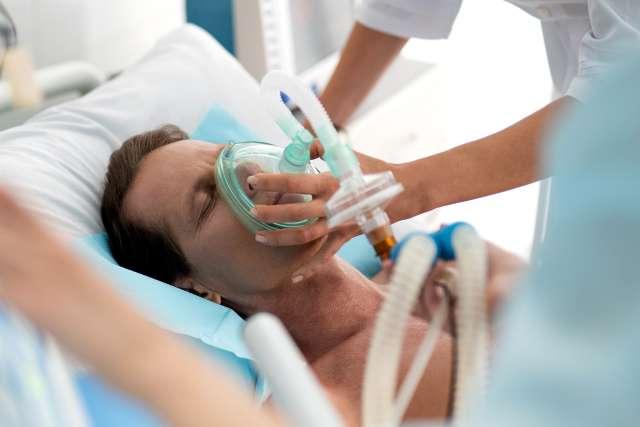 Middle aged man getting mechanical ventilation in hospital using respiratory equipment